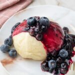 Steamed bun with blueberry sauce and yogurt on a white plate.