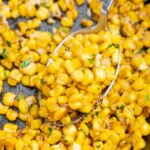 A close up photo of sauteed corn in a cast iron pan.