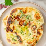 A stack of garlic Naan bread on a plate.